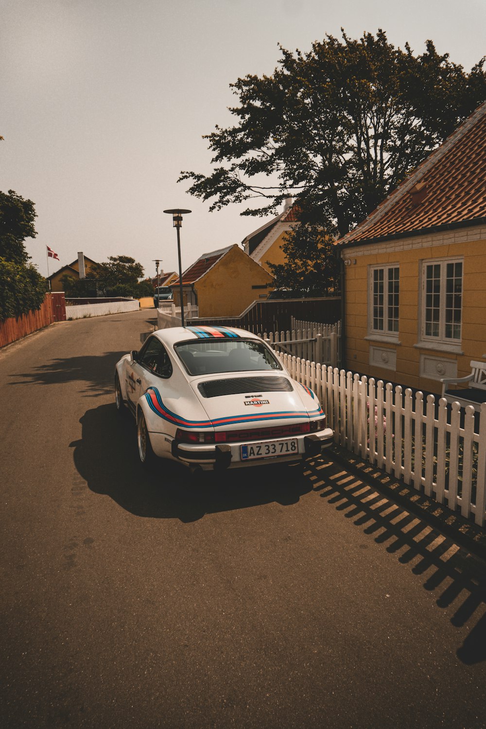 a white car parked in front of a yellow house