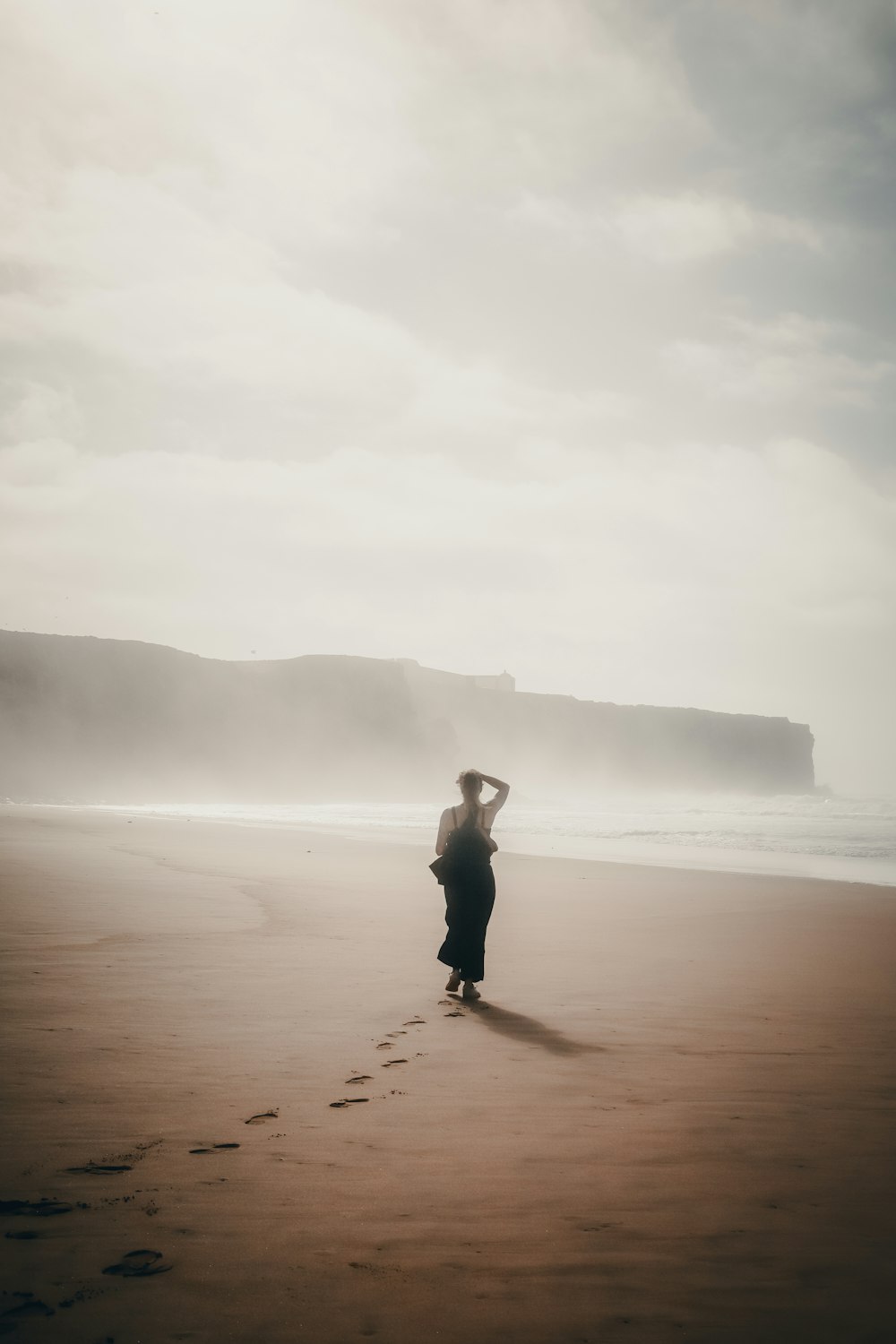 a person standing on a beach next to the ocean