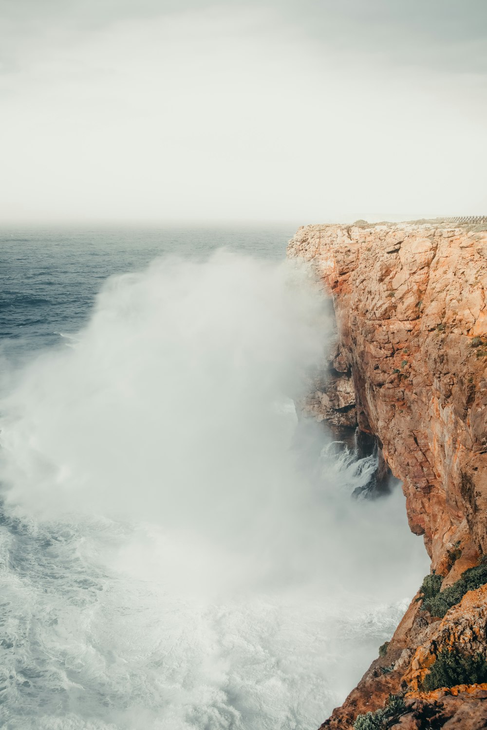 a large wave crashing into a rocky cliff