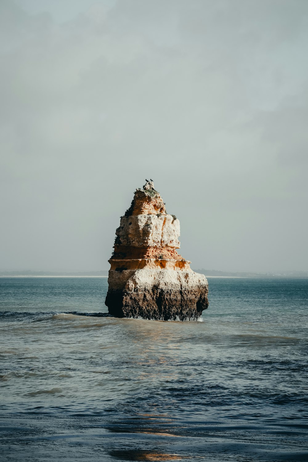 a large rock sticking out of the ocean