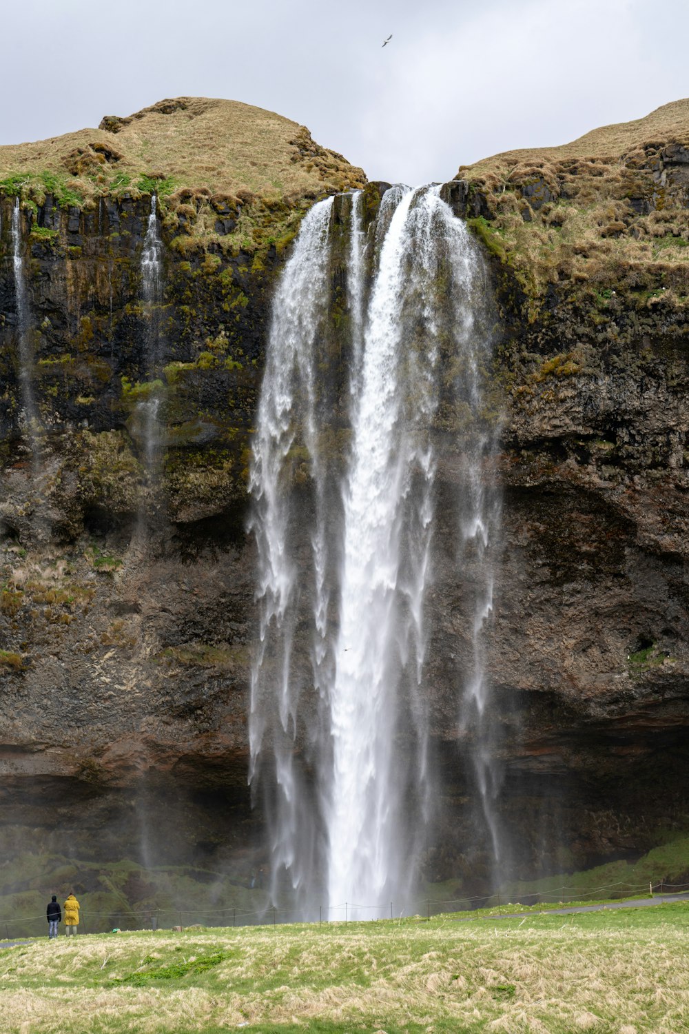 a large waterfall with a person sitting under it
