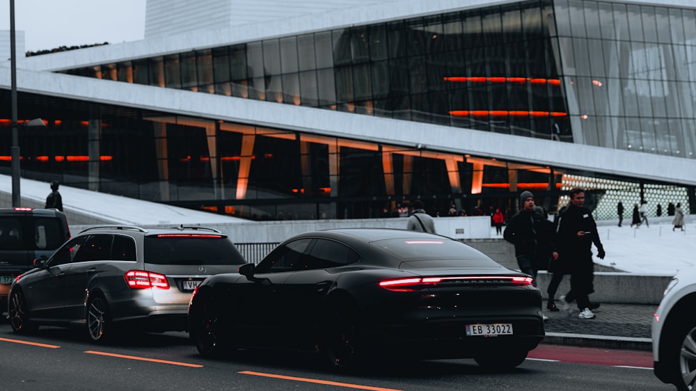 a group of cars driving down a street next to a tall building