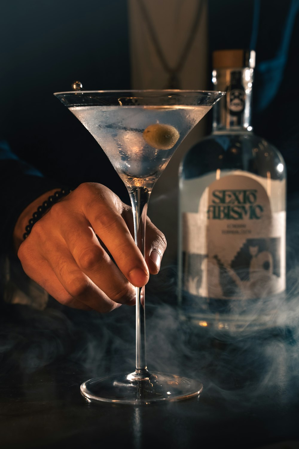 a person holding a martini glass with smoke coming out of it