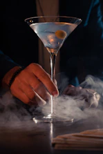 Elegant cocktail glass with a smoky garnish against a dark backdrop.
