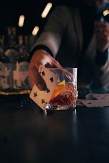 a person holding a card over a glass of alcohol
