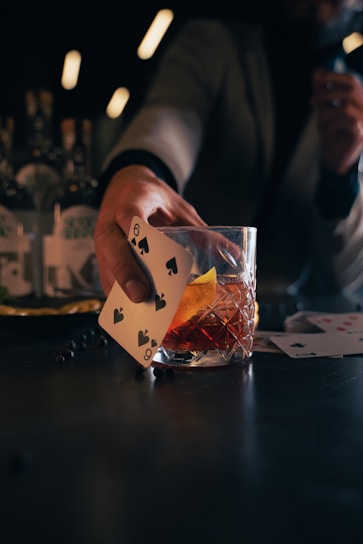 a person holding a card over a glass of alcohol