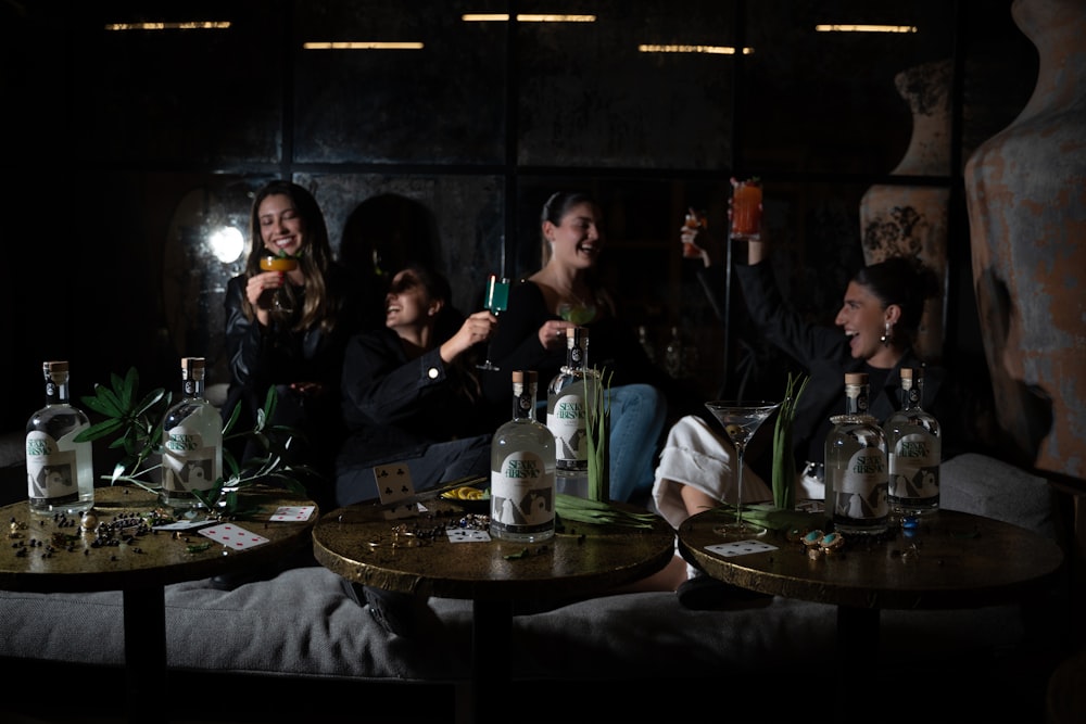 a group of people sitting around a table with bottles on it