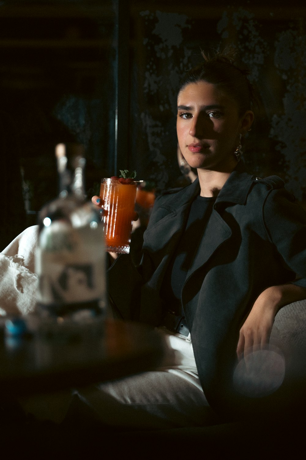 a woman sitting on a couch holding a drink