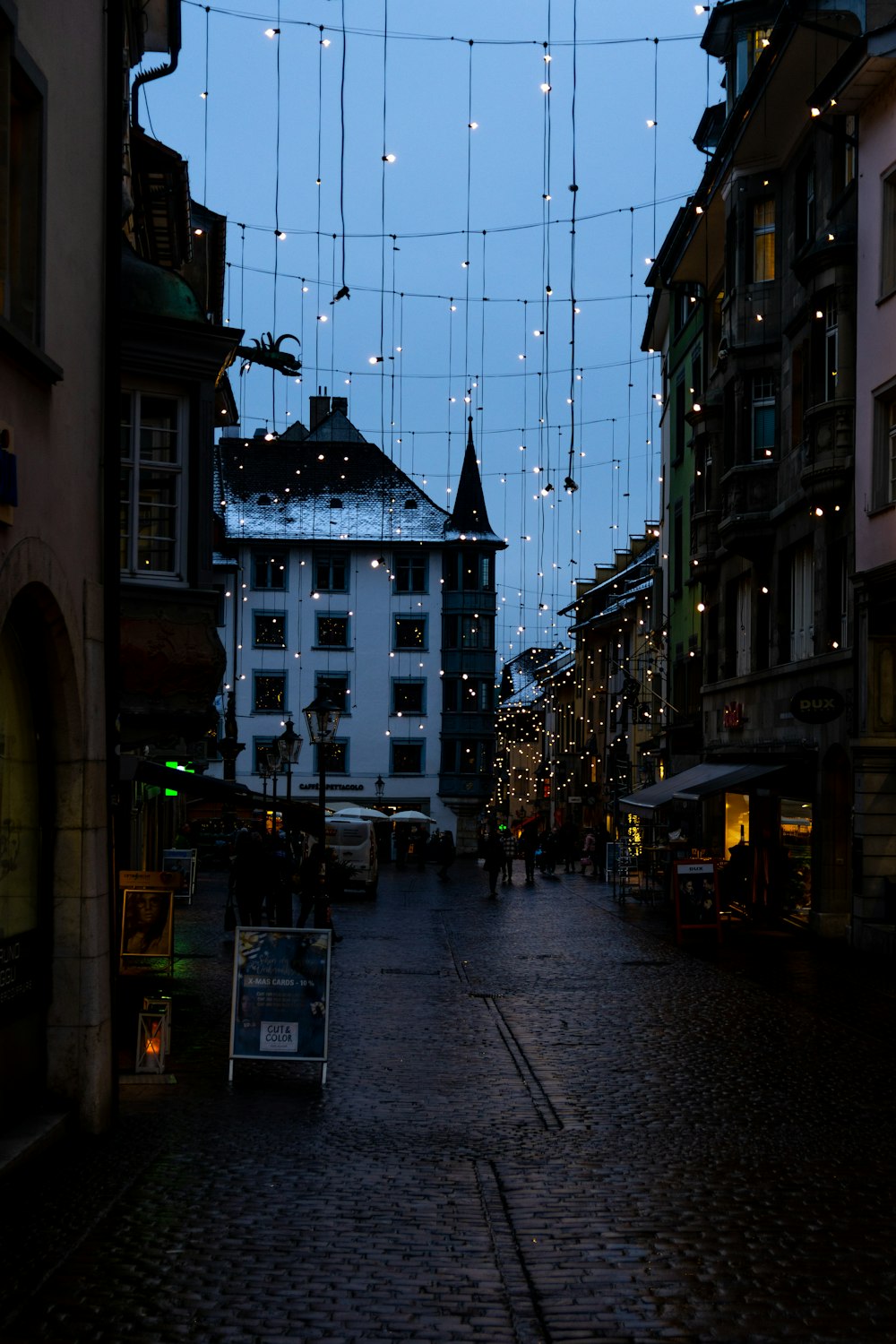 a cobblestone street is lit up with christmas lights