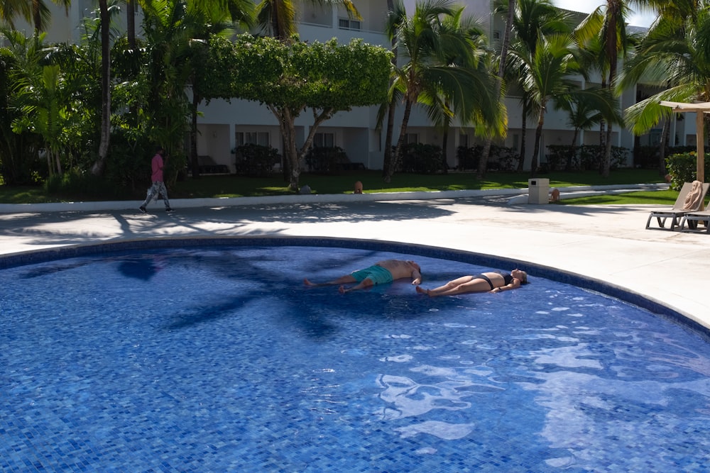 a woman swimming in a pool with palm trees in the background