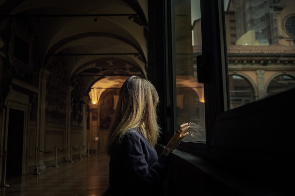 a woman looking out a window at a building