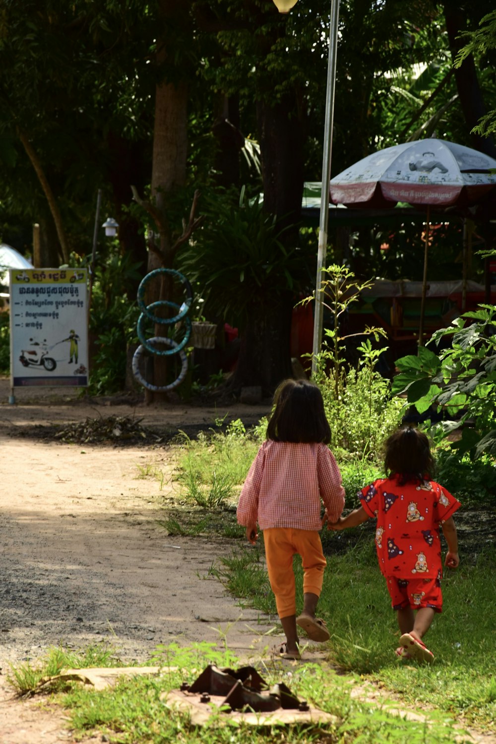 two little girls walking down a dirt road