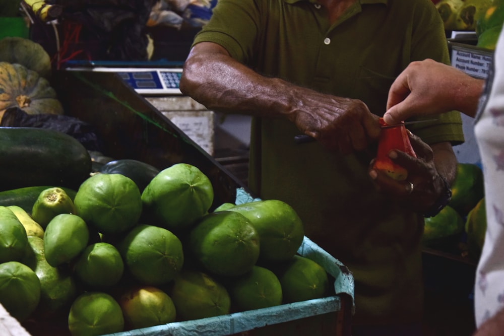 a man standing in front of a box of fruit