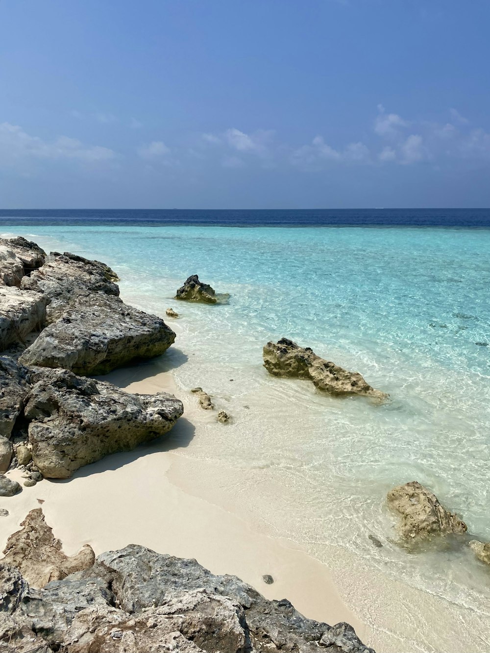 a beach with rocks and clear blue water