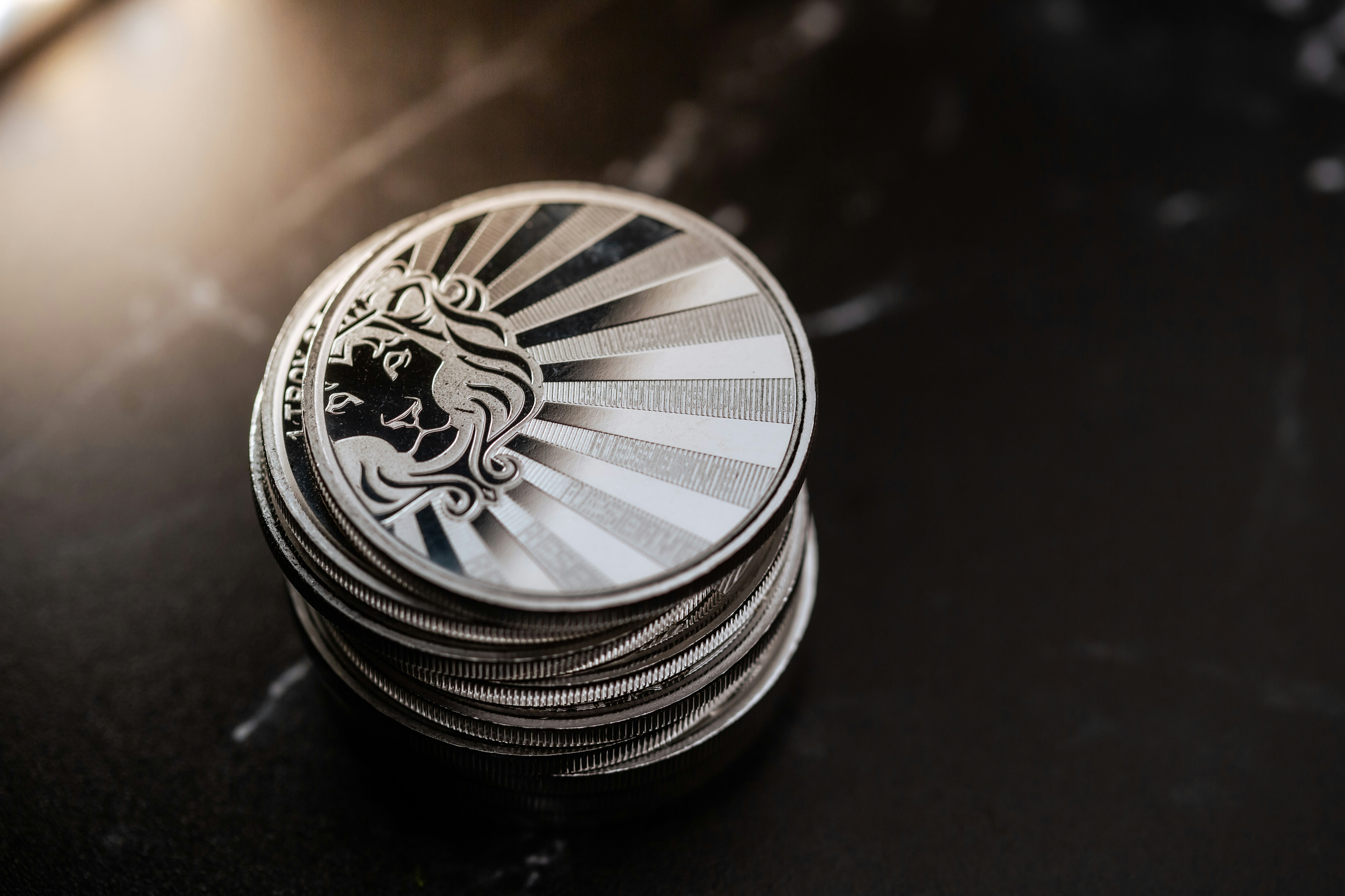 Scottsdale Silver 1 oz Reserve Rounds sitting in a pile on a light and dark background. Please give a shoutout to Scottsdale Mint if able! Shop online for the most beautiful bullion at ScottsdaleMint.com!