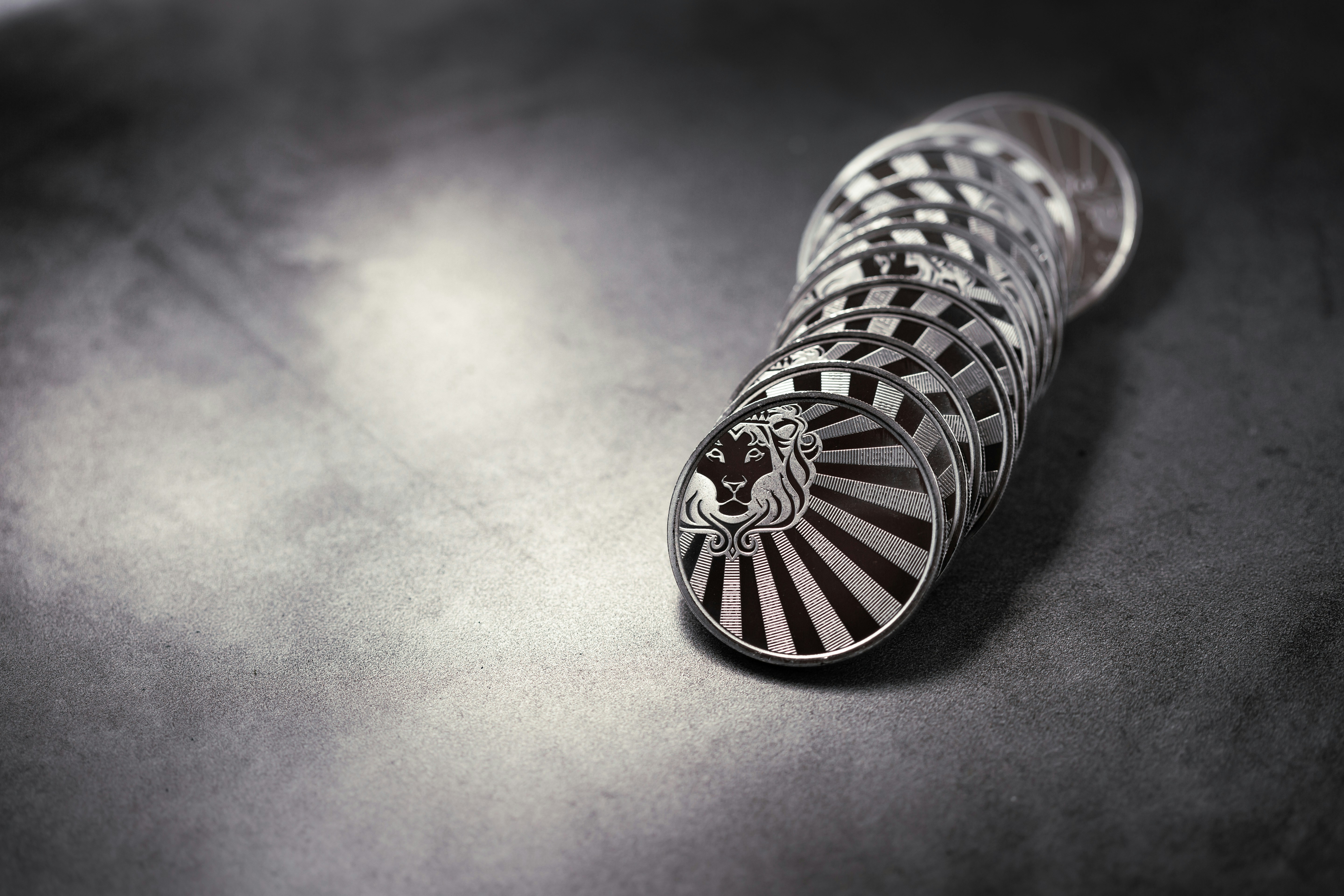 Scottsdale Silver 1 oz Reserve Rounds sitting in a pile on a light and dark background. Please give a shoutout to Scottsdale Mint if able! Shop online for the most beautiful bullion at ScottsdaleMint.com!