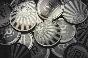 A collection of silver coins featuring a lion's head surrounded by sunburst rays and inscriptions such as 'Scottsdale', '1 TROY OZ', and 'RESERVE'. The design elements are embossed and the coins are metallic and reflective.