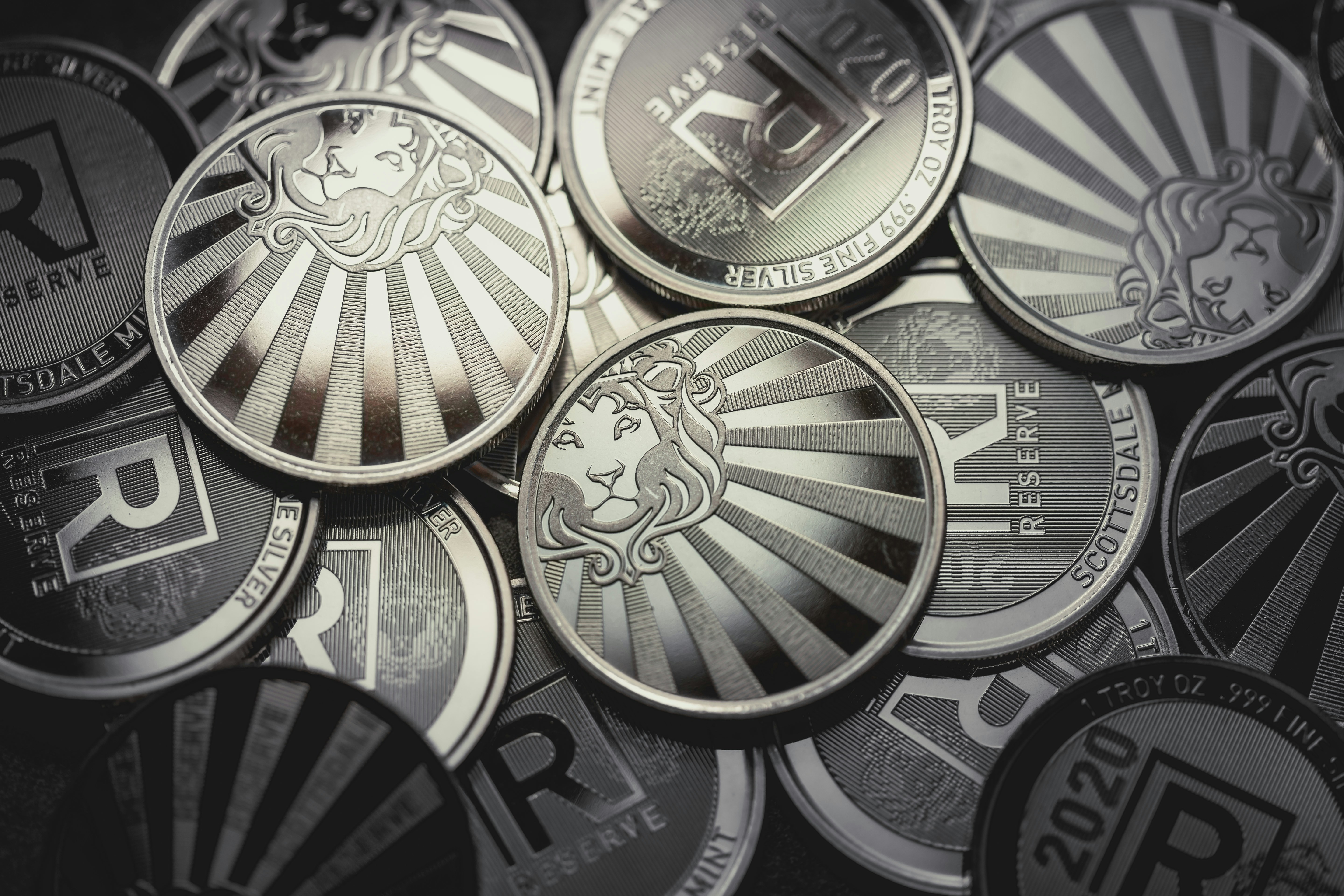 Scottsdale Silver 1 oz Reserve Rounds sitting in a pile on a light and dark background. Please give a shoutout to Scottsdale Mint if able! Shop online for the most beautiful bullion at ScottsdaleMint.com!