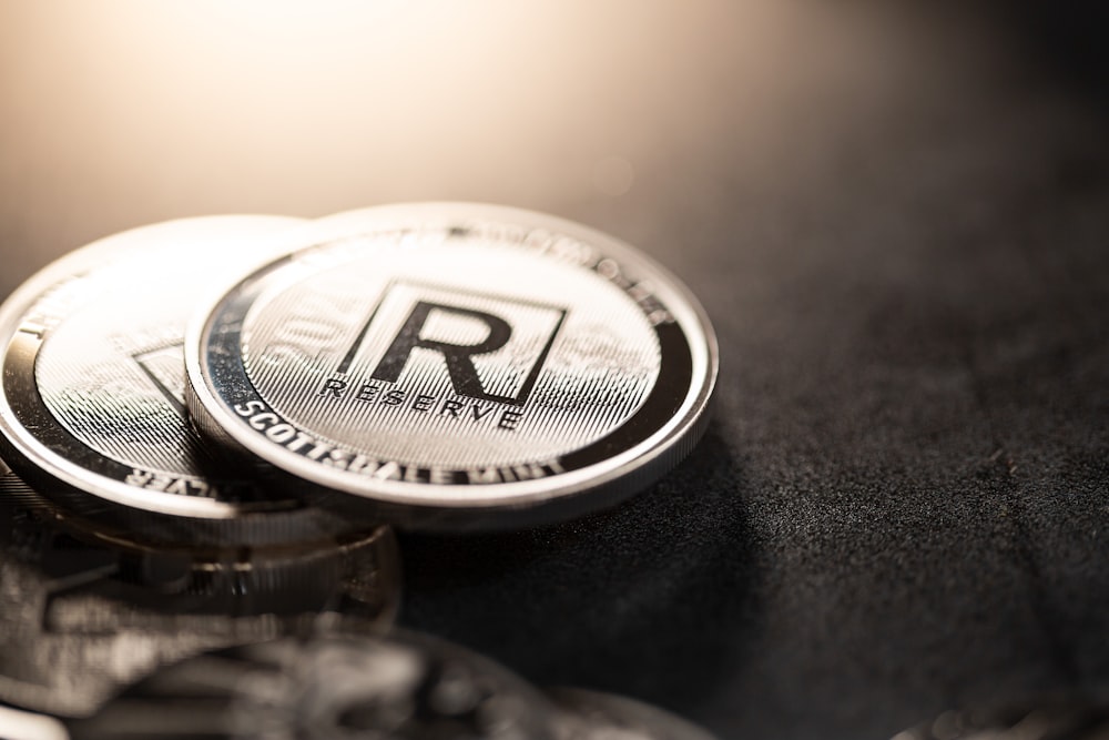 a close up of two silver coin on a black surface