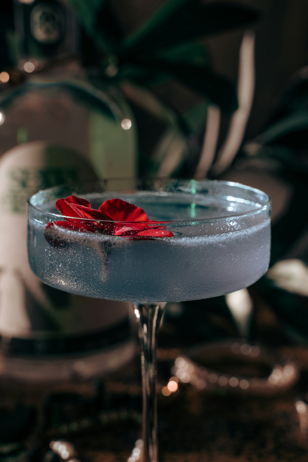 a blue cocktail with a red flower on the rim