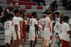 High school basketball team in bold red and black apace uniforms celebrating a win on the court.