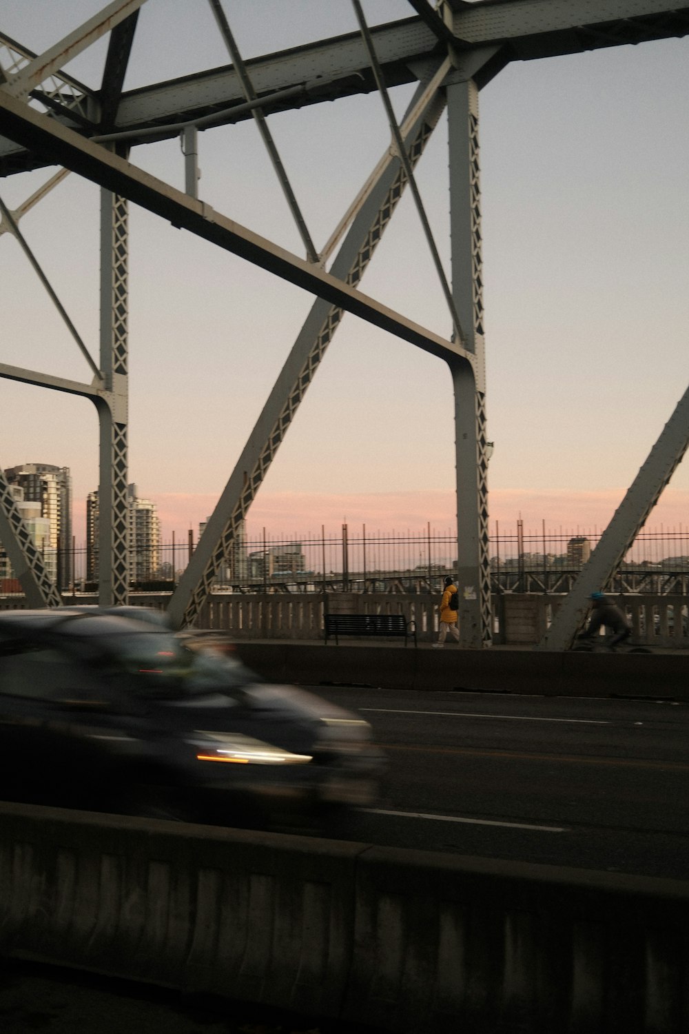 a car driving over a bridge with a city in the background