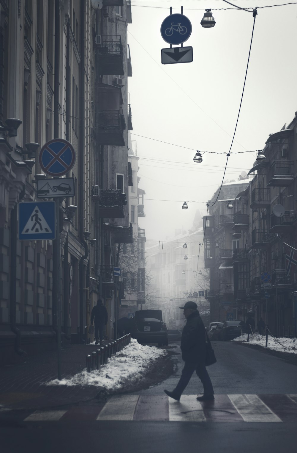 a person walking across a cross walk in the snow