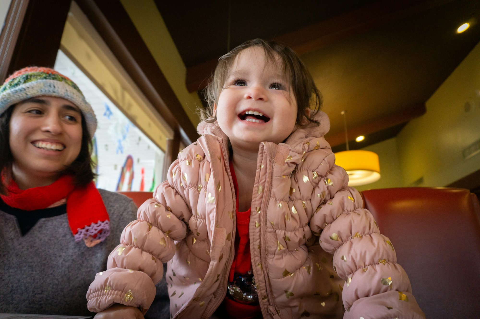 a little girl sitting next to a woman at a table