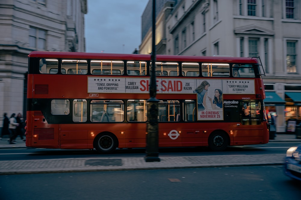 a red double decker bus driving down a street