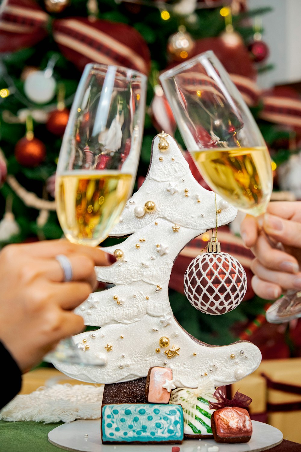 a couple of people holding wine glasses in front of a christmas tree
