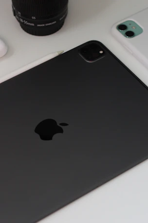 Close-up of hands working on a tablet surrounded by smart gadgets and tech accessories on a clean white desk.