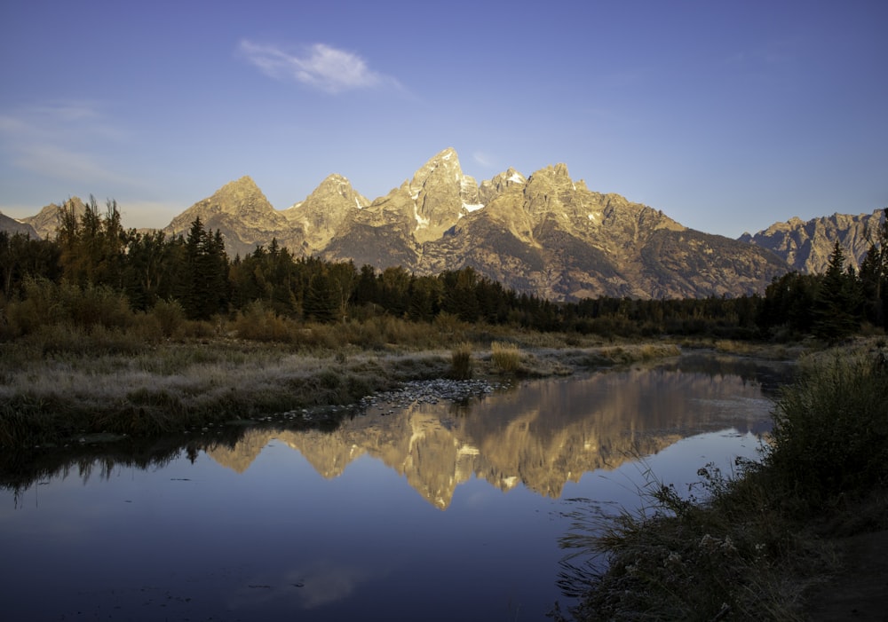 the mountains are reflected in the still water of the river