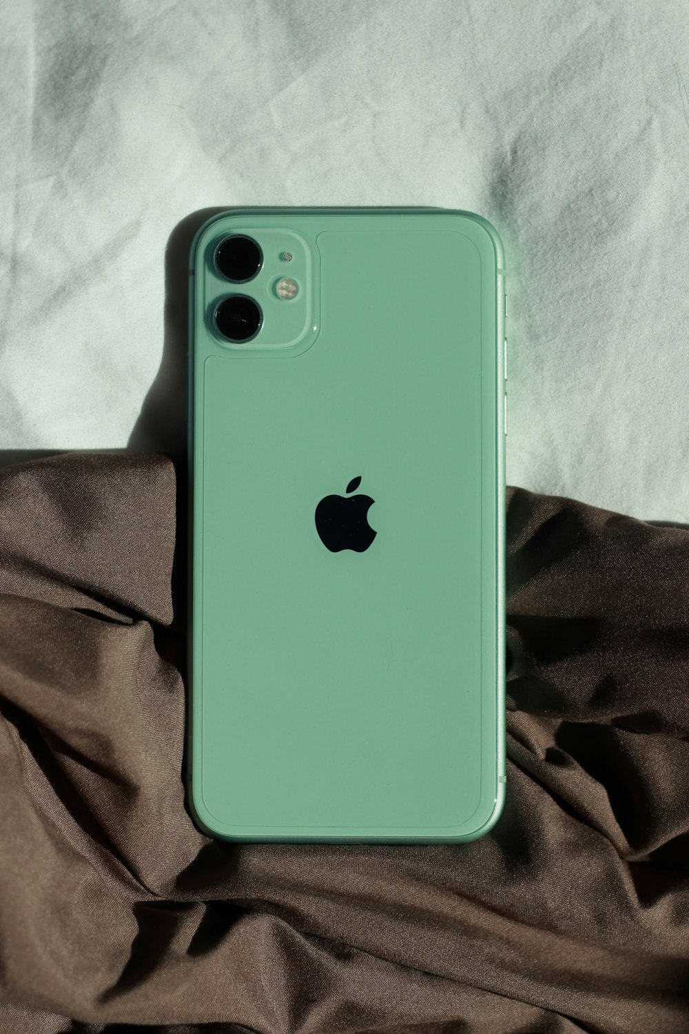 a green iphone sitting on top of a bed