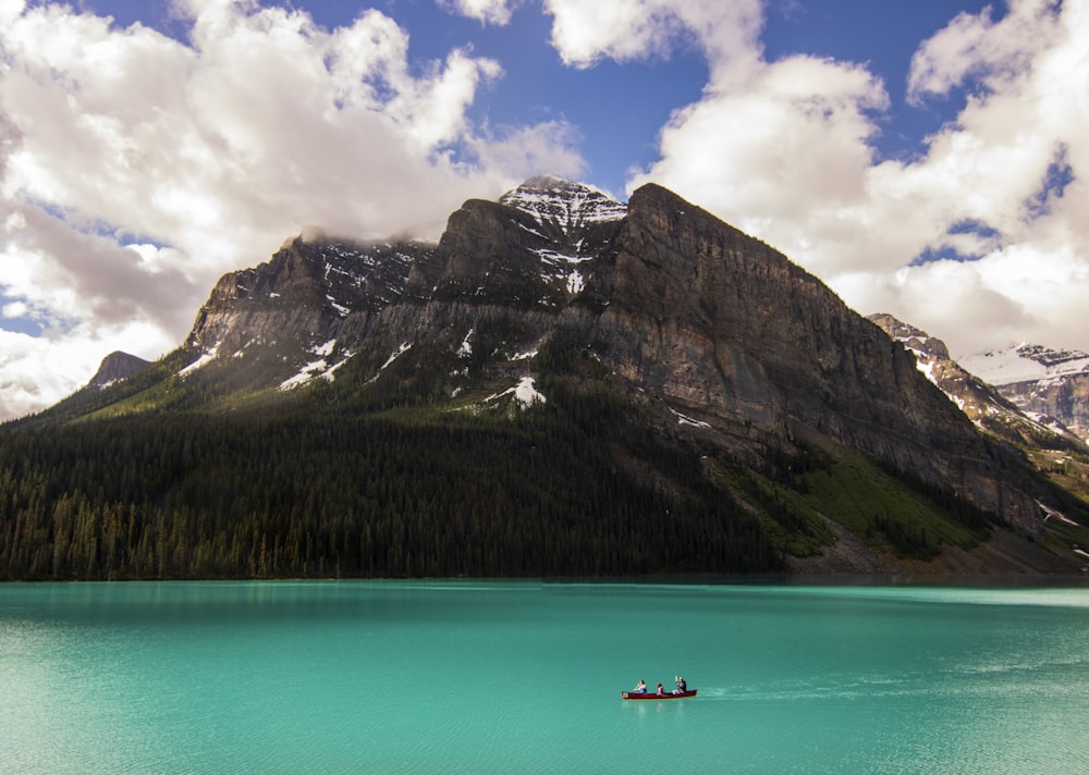 a boat floating on top of a lake surrounded by mountains