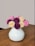 A close-up photo of a minimalist ceramic vase holding fresh wildflowers on a wooden table.
