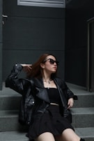 A model sitting on urban steps wearing a chic Prada-inspired outfit with subtle gold accents.