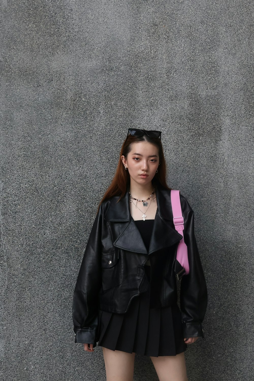 a young woman wearing a black jacket and a pink tie