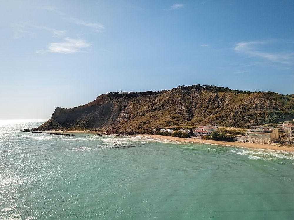 an aerial view of a beach with a cliff in the background