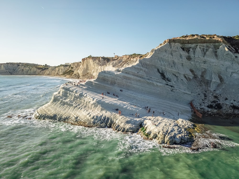 a group of people standing on top of a cliff next to the ocean