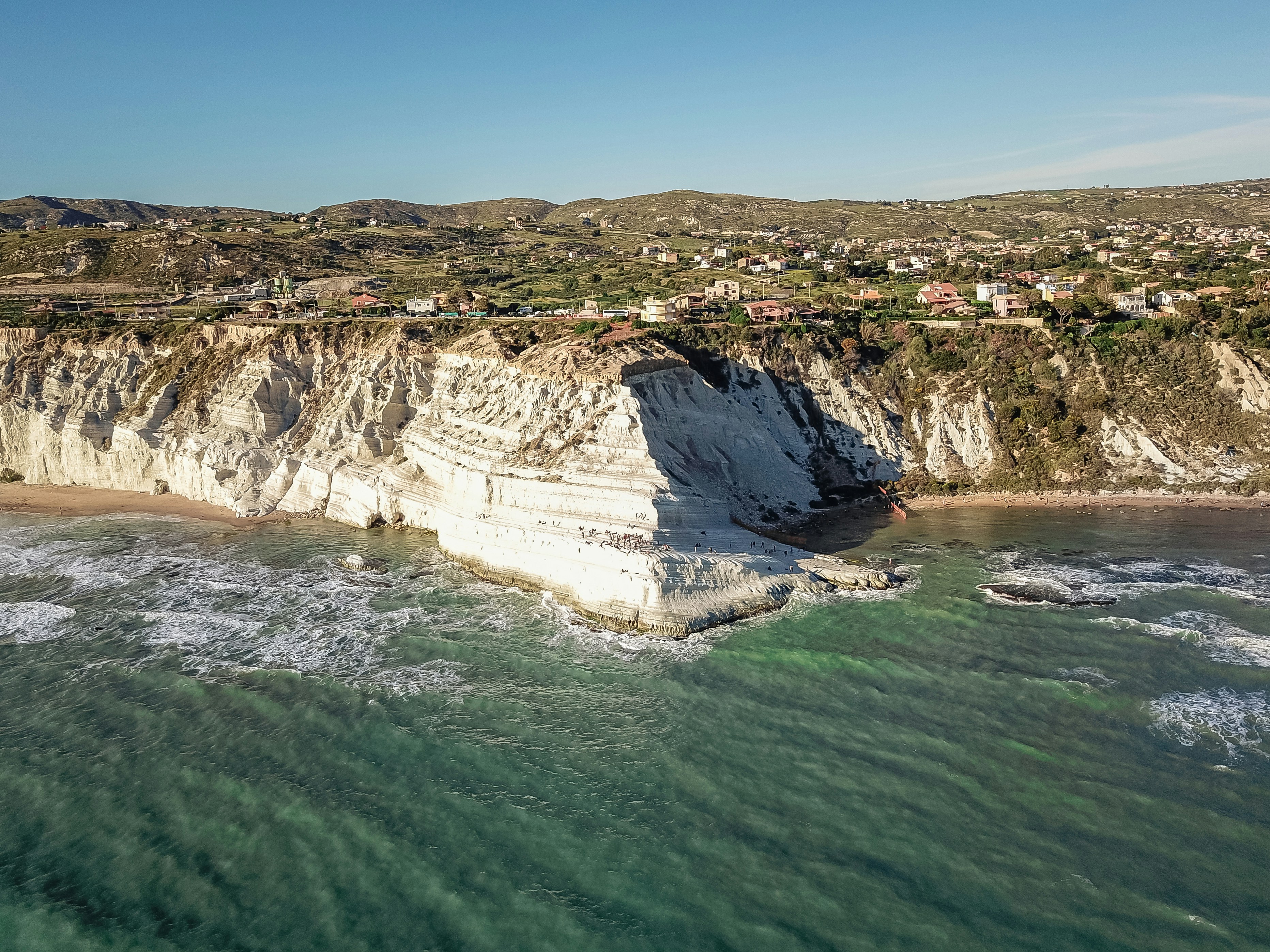 an aerial view of a beach with a cliff in the background
