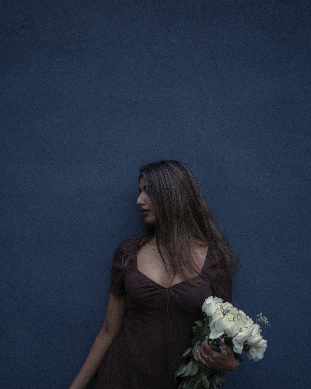 a woman in a brown dress holding a bouquet of flowers
