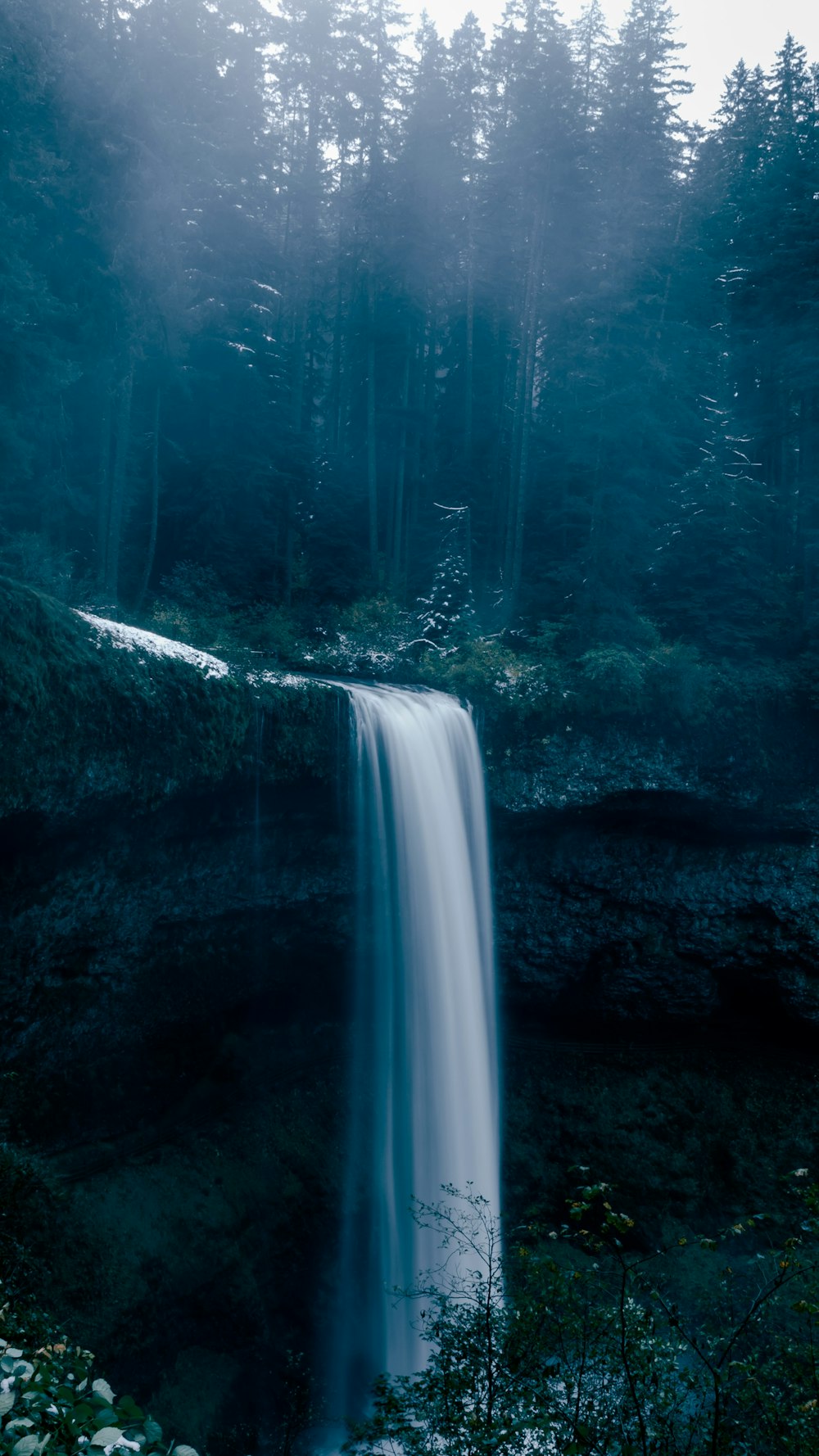 a very tall waterfall in the middle of a forest