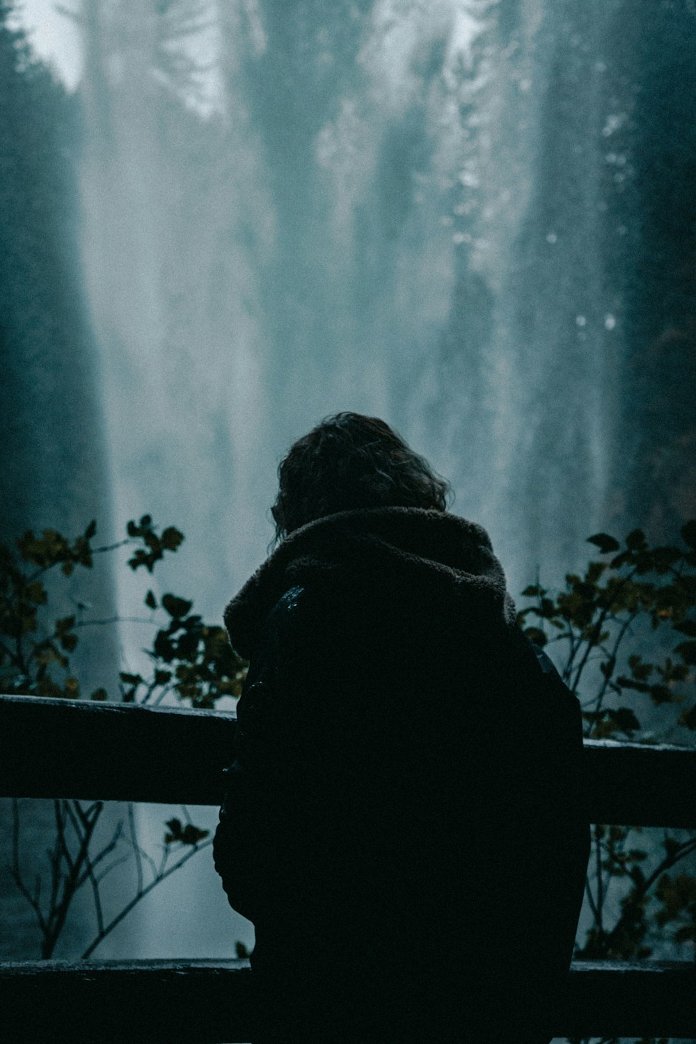 Eine Person sitzt auf einer Bank vor einem Wasserfall