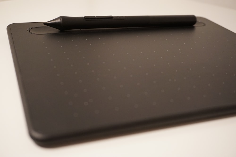 a pen sitting on top of a black tablet