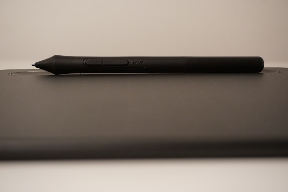 a black pen sitting on top of a laptop computer