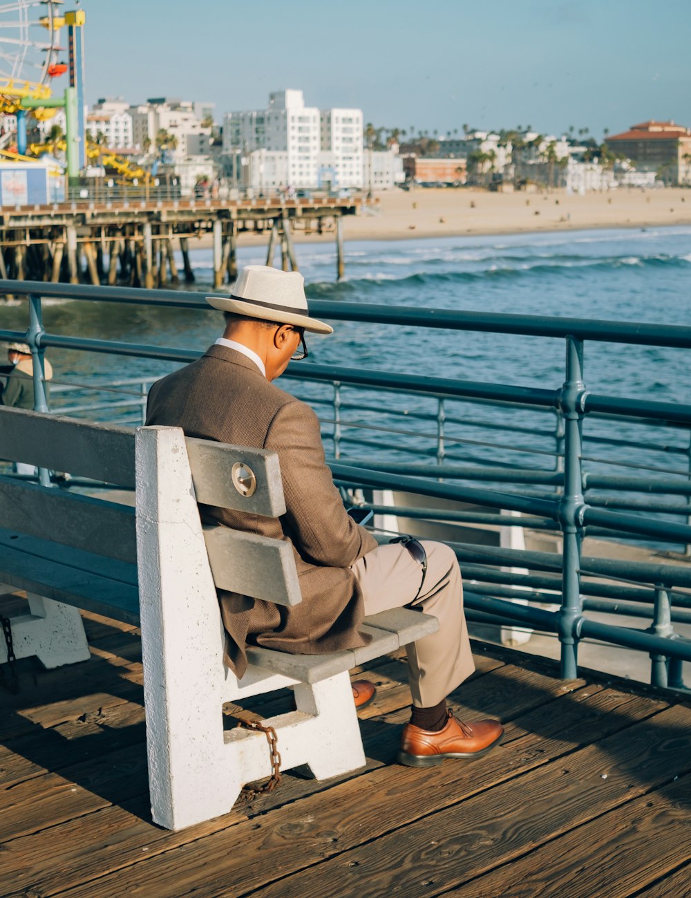 a man in a suit and hat sitting on a bench