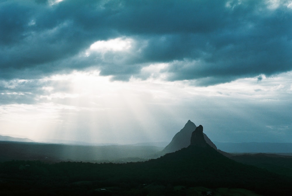 the sun shines through the clouds over a mountain