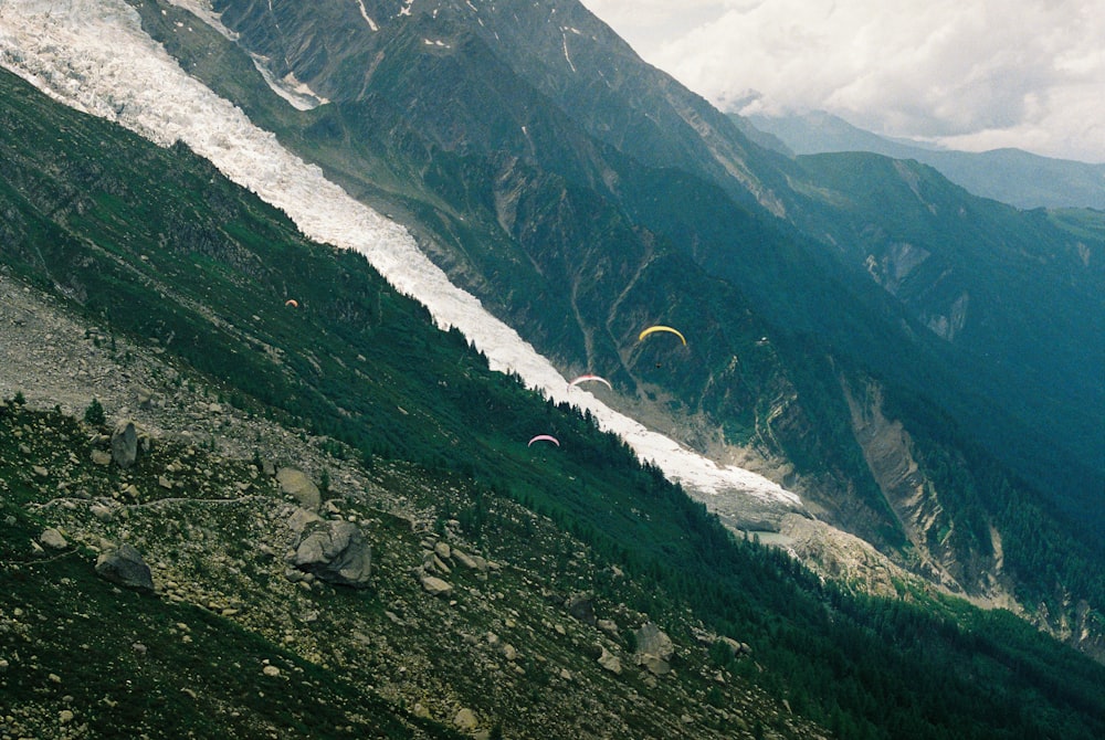 a group of paraglides flying over a mountain range