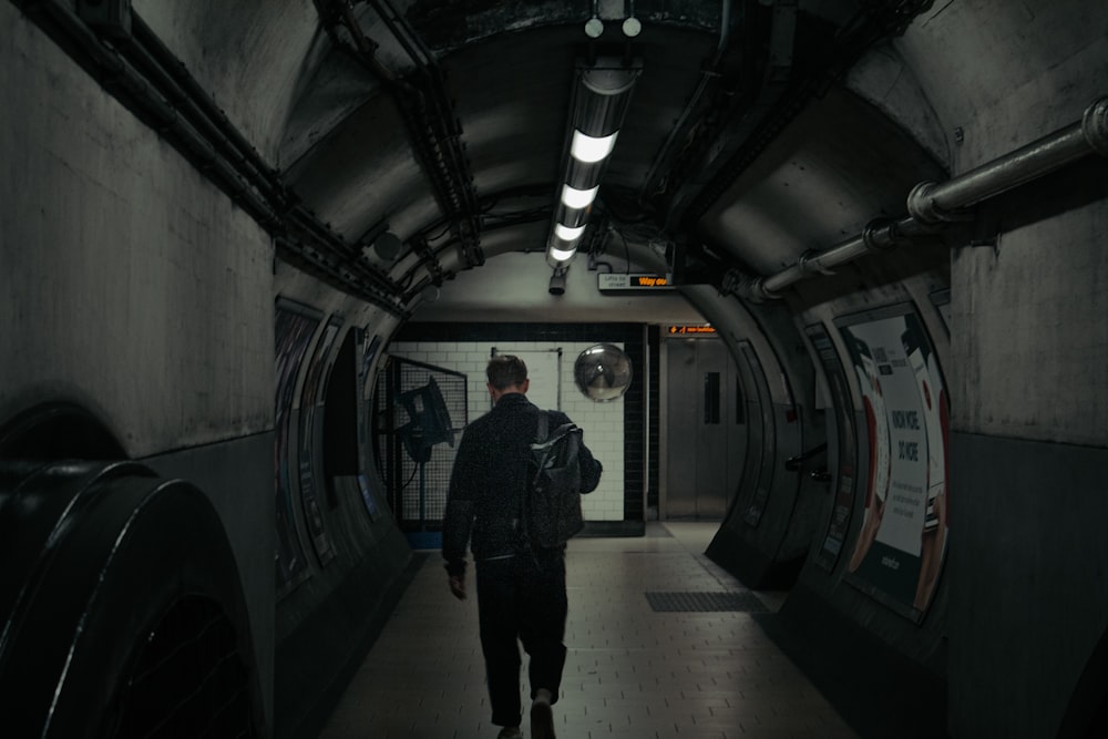 a man is walking down a dark tunnel