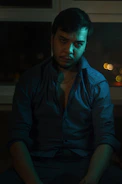 A cinematic still from Eduardo del Llano's latest film project showing a thoughtful character in a dimly lit room.